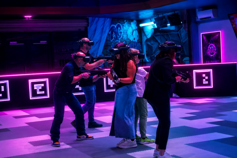Groupe de joueurs en casques VR pointant leurs armes laser lors d'un escape game en réalité virtuelle
