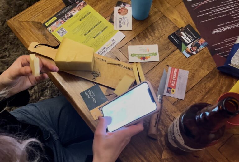 Joueur tenant un morceau de fromage et son téléphone parmi les indices du jeu "Escape Games L'Apéro"