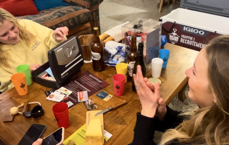 Groupe d'amis autour d'une table avec un coffre à combinaison et des bouteilles lors du jeu "Escape Games L'Apéro"