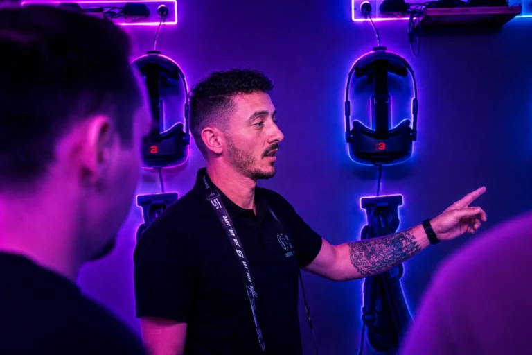 Un animateur Virtual Arena explique le déroulement d'une session VR à des clients dans une salle aux néons violets