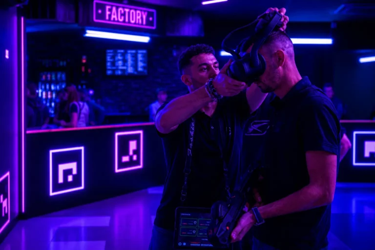Un animateur Virtual Arena ajuste le casque VR équipé d'un pistolet laser d'un client