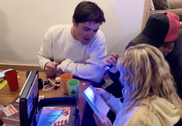 Deux joueurs examinant un indice à la lampe UV lors du jeu "Escape Games L'Apéro"
