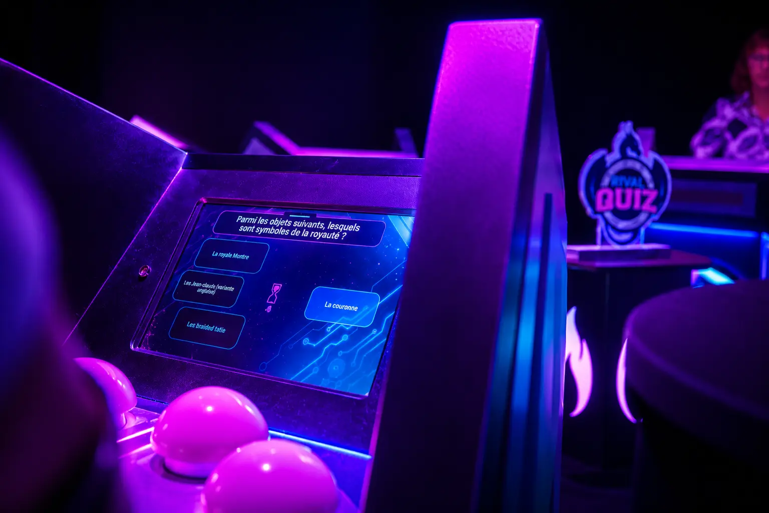 Écran tactile du jeu "Rival Quiz" affichant une question à choix multiples avec boutons lumineux roses