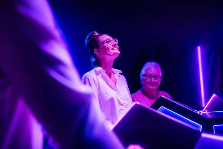 Deux joueuses souriantes derrière leur pupitre lors d'une partie de Rival Quiz aux néons violets