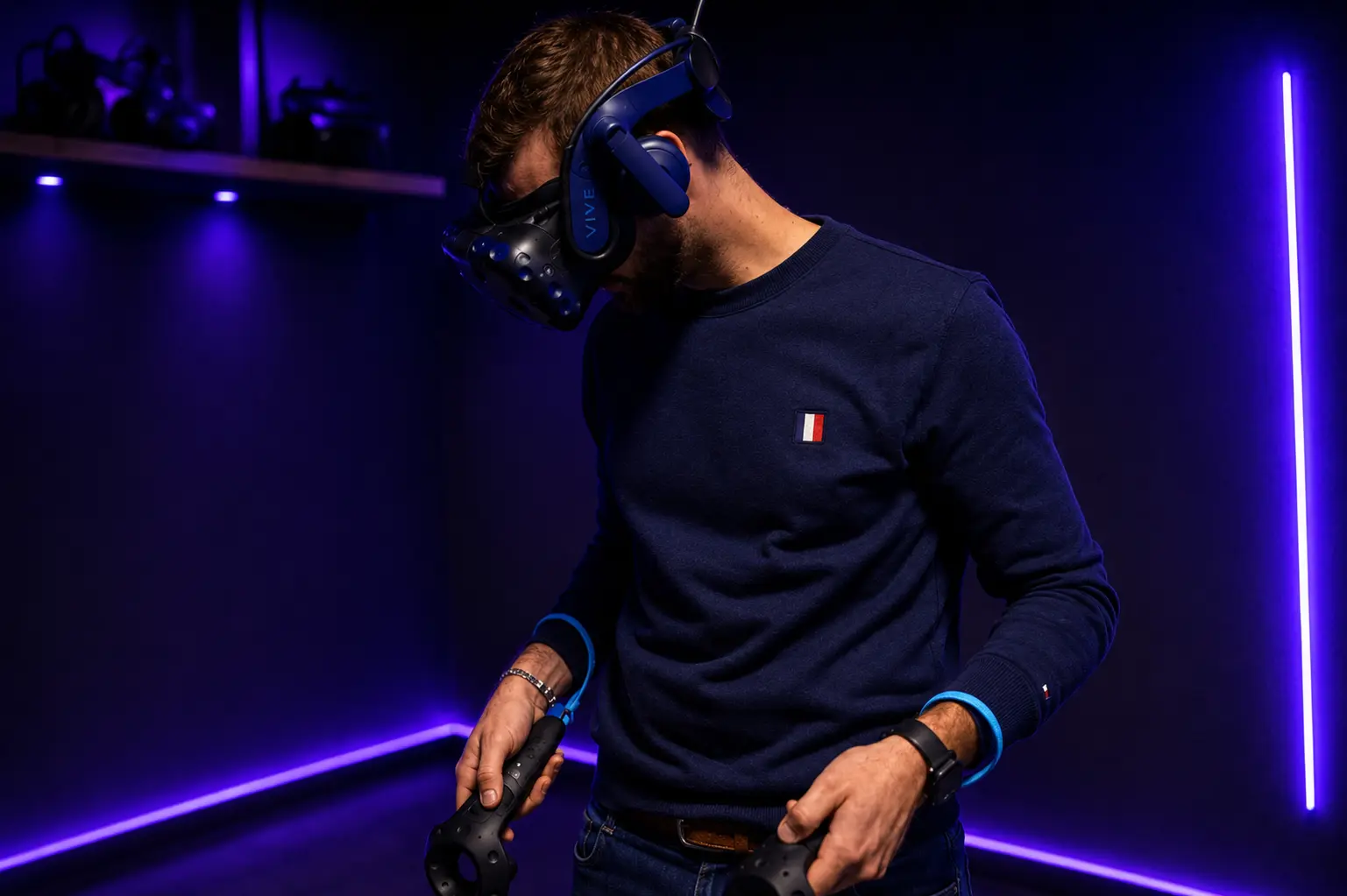Joueur équipé d'un casque VR HTC Vive et de manettes dans une salle d'escape game en réalité virtuelle