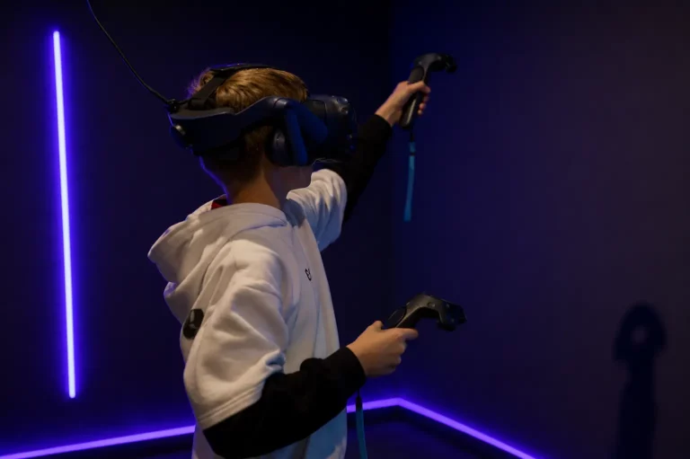 Adolescent équipé d'un casque VR levant le bras avec sa manette lors d'un escape game en réalité virtuelle